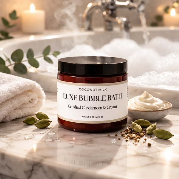 Jar of Luxe Bubble Bath with coconut milk on a bathroom counter with a bathtub in the background.