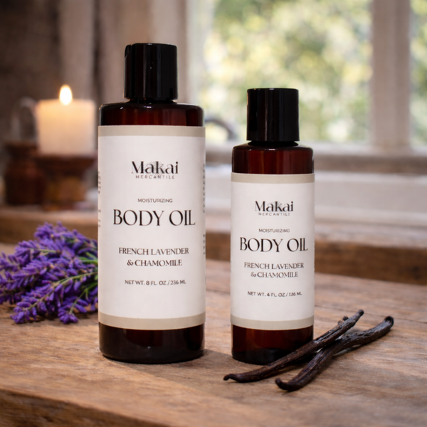 Two bottles of Makai body oil on a wooden surface with lavender and vanilla beans.