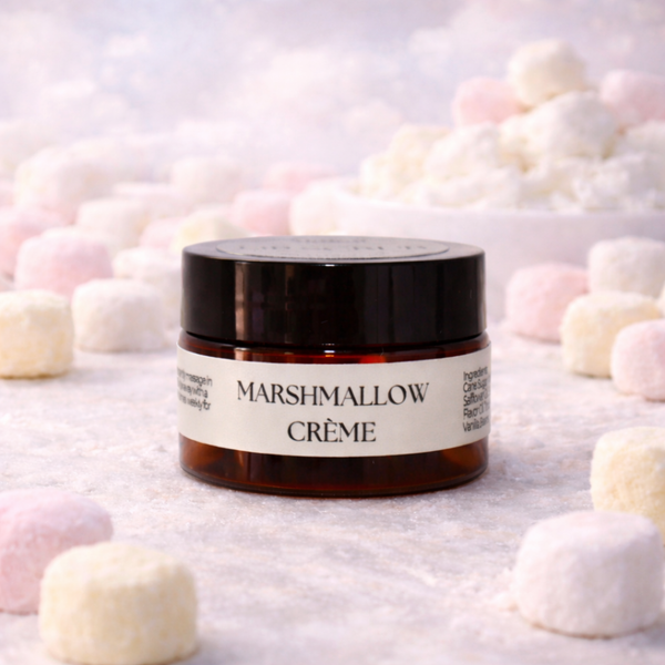 Jar of Marshmallow Crème  Lip Scrub surrounded by marshmallows on a light background