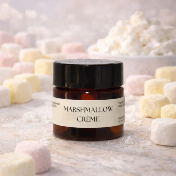 Jar of Marshmallow Creme  Luxe Lip Butter surrounded by marshmallows on a light background