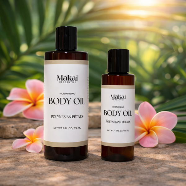 Two bottles of Makai Body Oil with plumeria flowers and greenery in the background