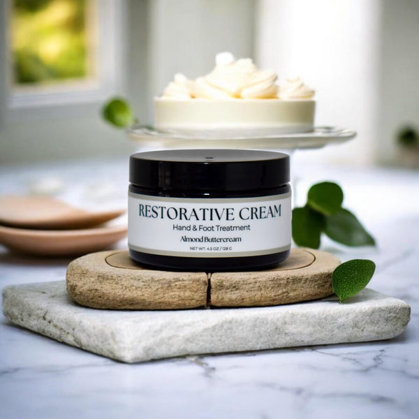 Restorative cream jar on a marble surface with a blurred background in Almond Buttercream scent