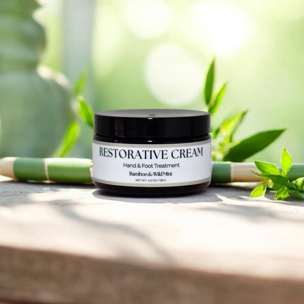Restorative cream jar with greenery in the background in Bamboo & Wild Mint scent