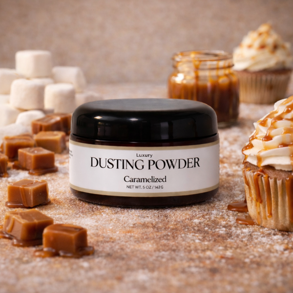 Jar of 'Luxury Dusting Powder Caramelized' surrounded by caramel candies and cupcakes on a wooden surface.
