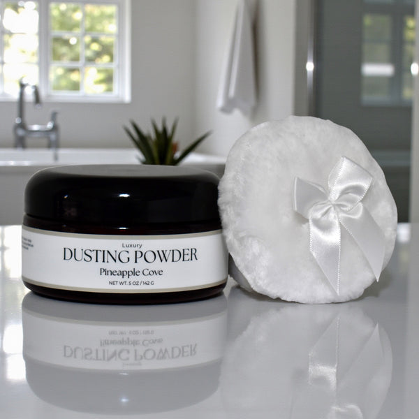 Dusting powder jar and round container with a bow on a reflective surface, bathroom setting.